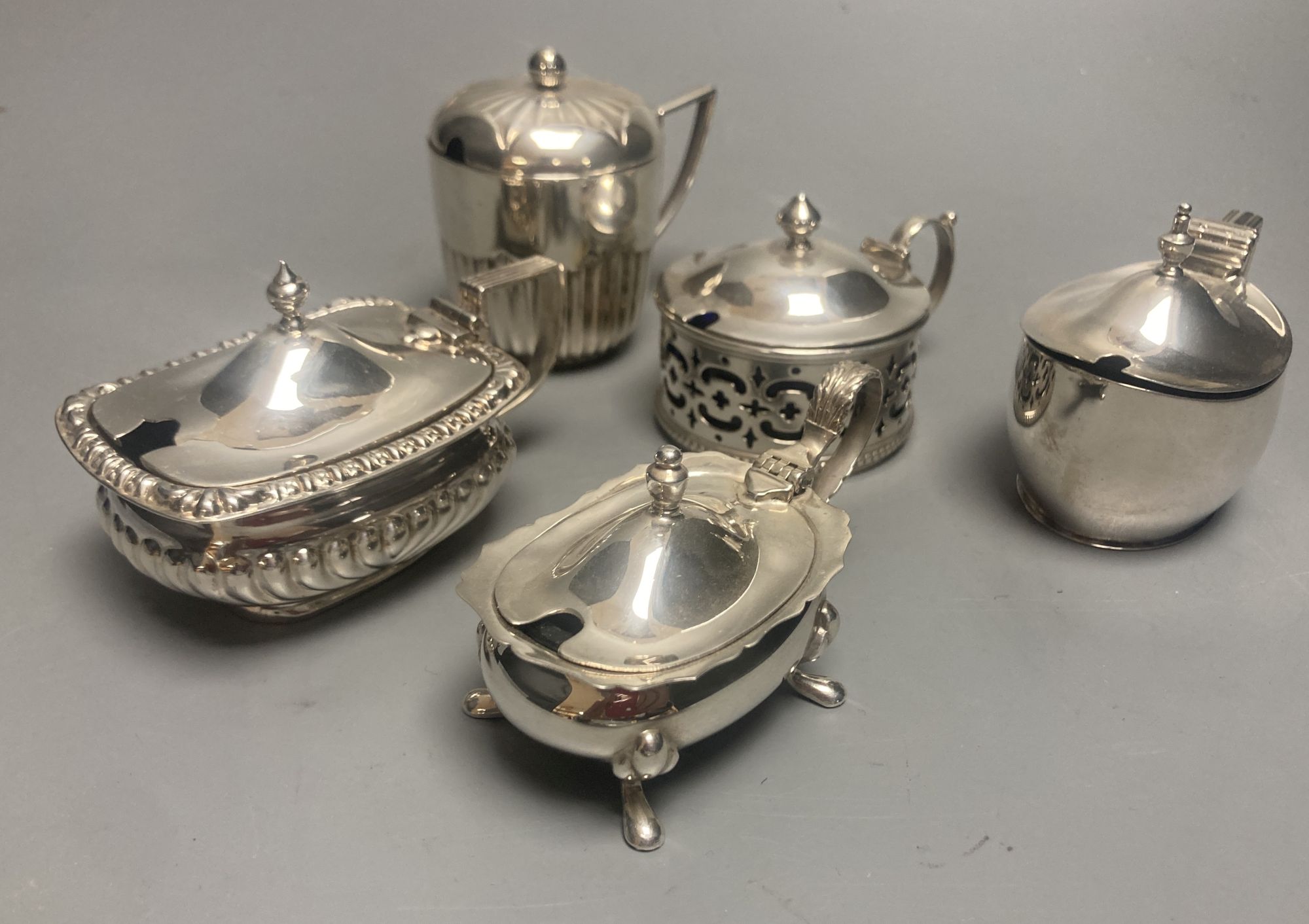 A late Victorian demi fluted silver mustard pot, London, 1894 and four other assorted later silver mustards.